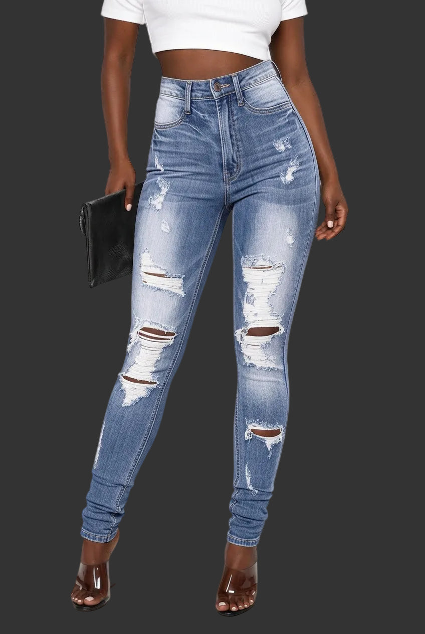 A model wearing high-waisted, light blue distressed skinny jeans with ripped details on the thighs and knees, paired with a white crop top and brown high-heeled sandals against a dark gray background.