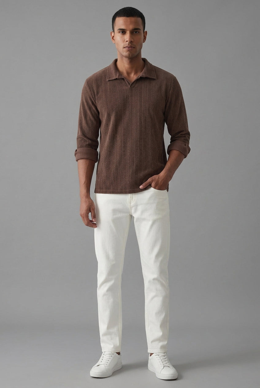 A man wearing a brown ribbed long-sleeve polo shirt with rolled-up sleeves and white pants
