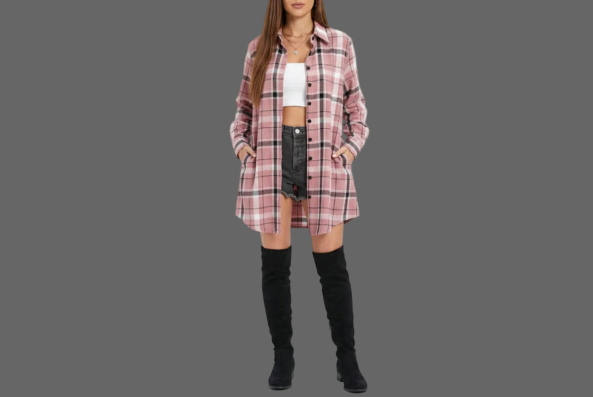 A woman wearing a pink, white, and black plaid button-up shirt over a white crop top and black denim shorts