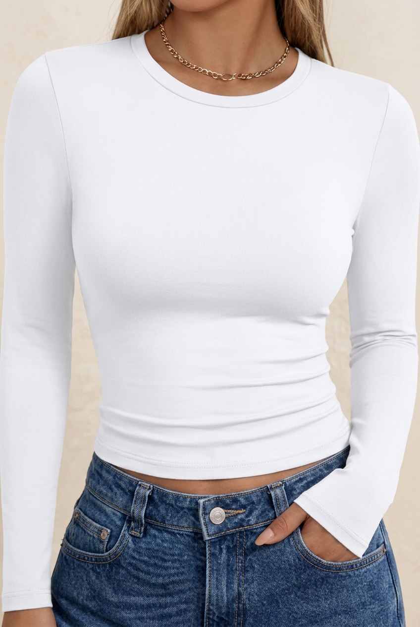 A woman wearing a fitted white long-sleeve crewneck top paired with blue jeans, shown from the neck to the hips against a plain white background.