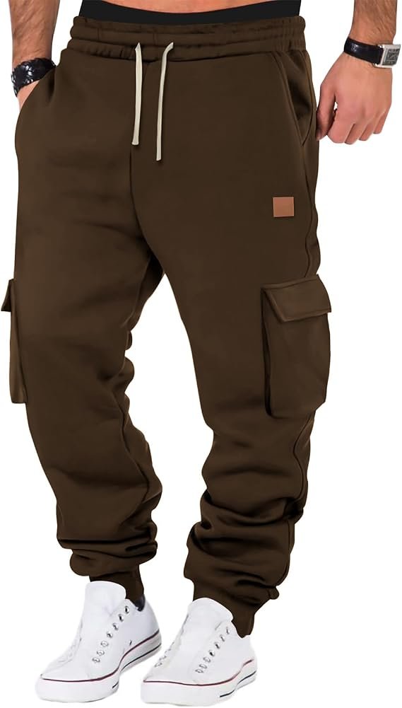 A person wearing brown cargo jogger sweatpants with white drawstrings, side cargo pockets, and elastic cuffs, paired with white sneakers against a plain white background.